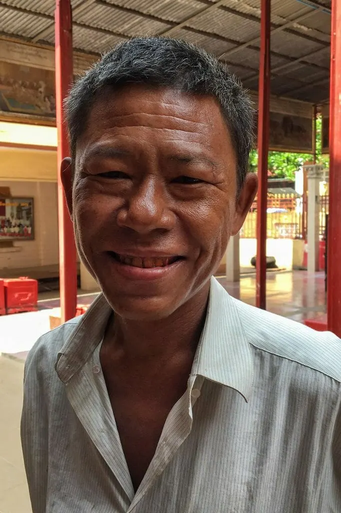 A man smiling while looking through the camera who helped me find a way around Mahamuni Pagoday in Mandalay