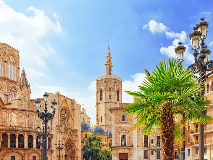 Gothic building and tower in the centre of Valenciana, with very grand street lights and a palm tree