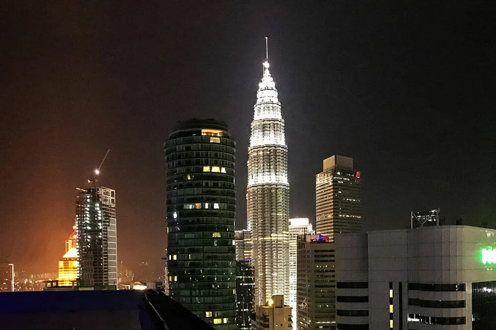 Night view of Petronas Towers lit up and surrounded by other buildings
