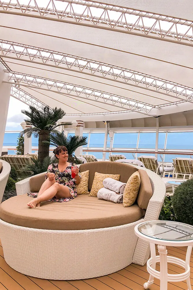 Me enjoying a cocktail, sitting on large round cushioned sofa on a cruise ship sundeck