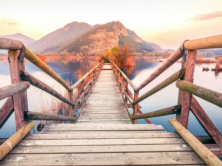 Wooden pontoon built over a lake with the mountains in the background at sunset