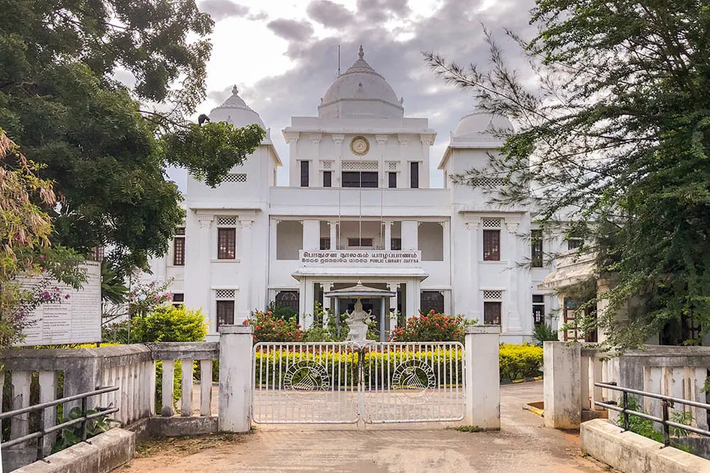 White building in the olonial style with trees and a garden around it