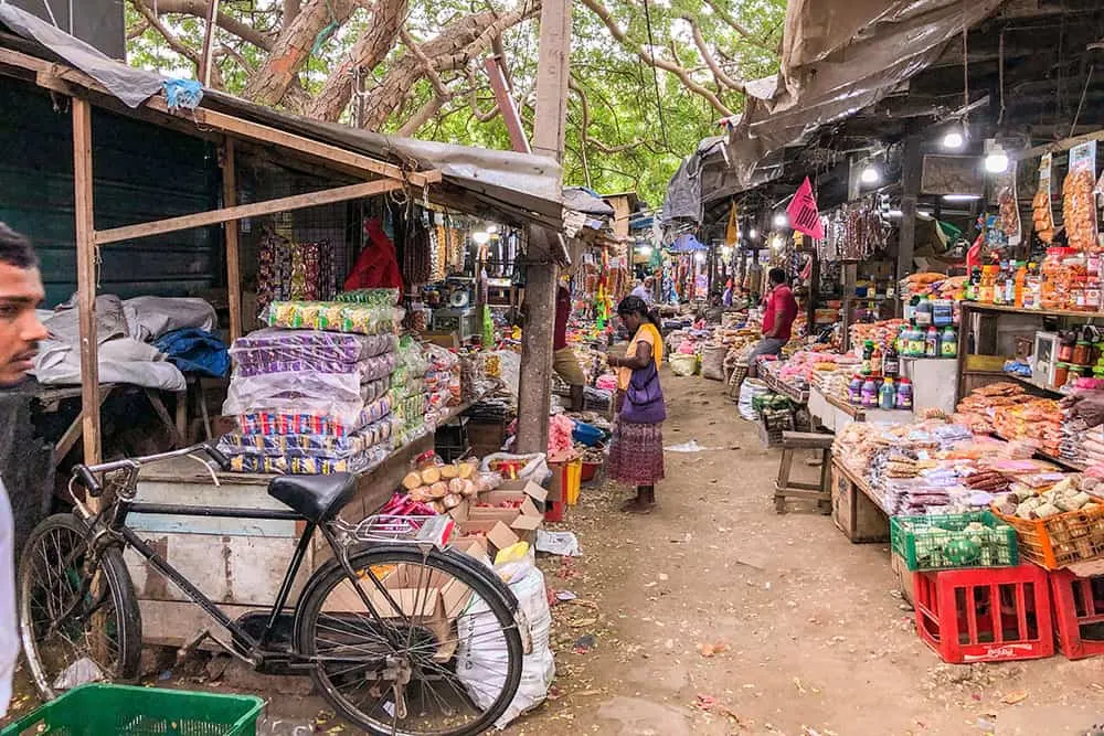 One of the top things to do in Jaffna is visiting Jaffna Market. Street market with shops selling local produce and a woman shopping.