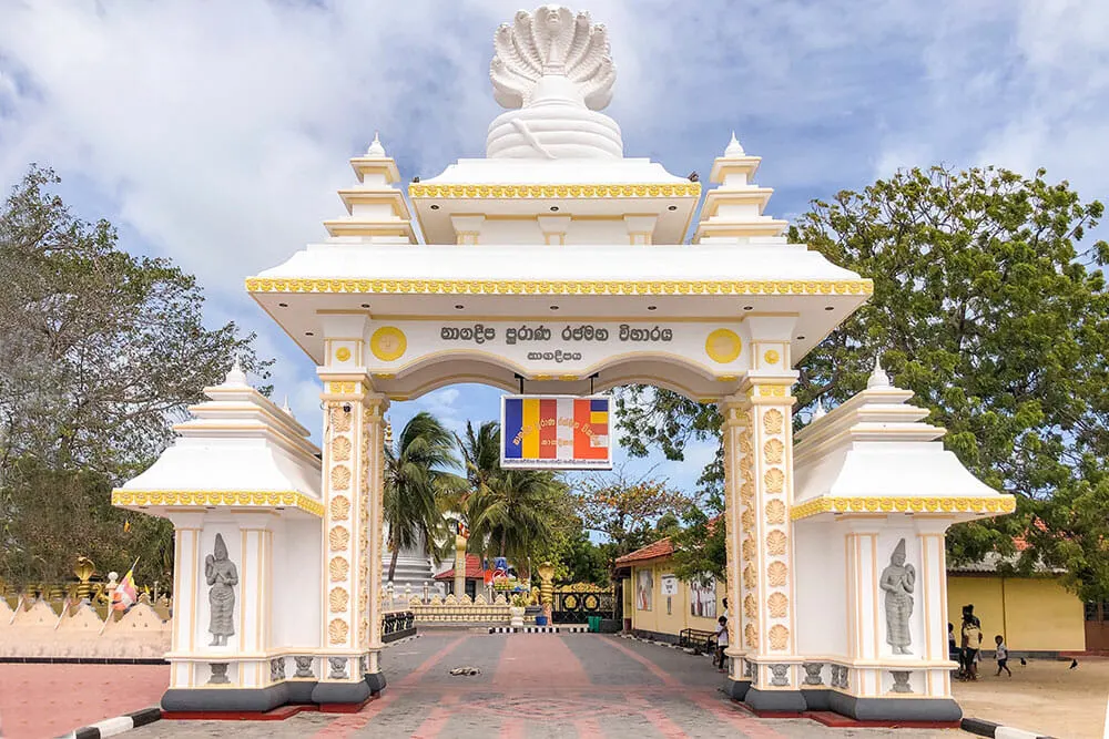 White gate with Sri Lankan writing and a Buddhist sign