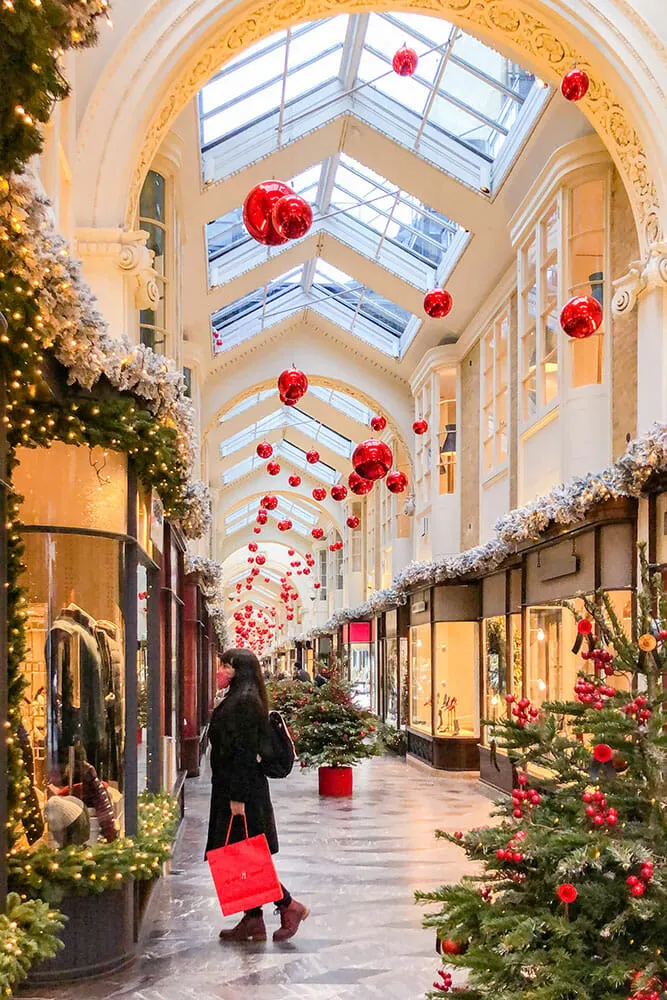 Me looking through a shop window inside a Victorian arcade decorated with Christmas baubles and tree