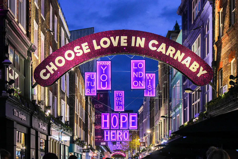 Christmas lights in Carnaby with an arch reading ' Choose Love in Carnaby' and neon messages reading 'hope', 'hero', 'you', 'london'