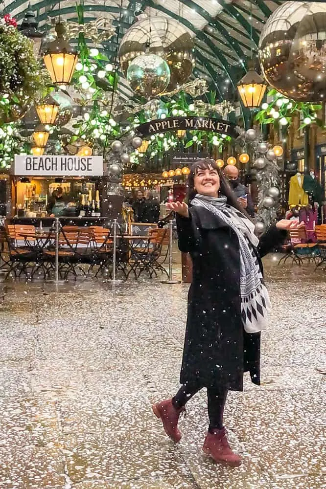 Me standing outside the market stalls sign 'Apple Market' trying to catch snowflakes with my hands