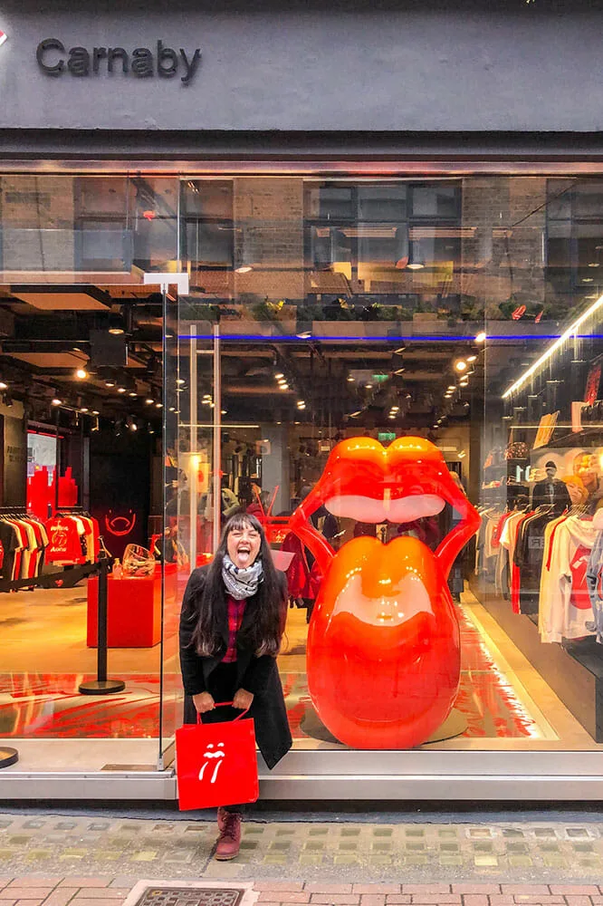 Me standing outside a shop window that displays the Rolling Stones tongue, mimicking it