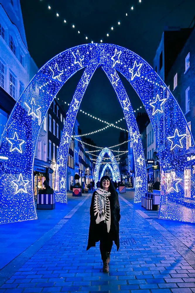 Me walking through Christmas lights in the shape of blue fairy light arches