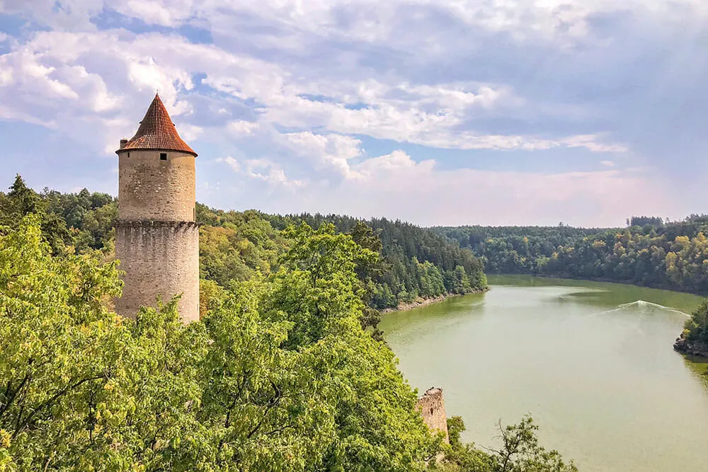 Castle tower perched on a high promontory surrounded by trees and overlooking a large reservoir