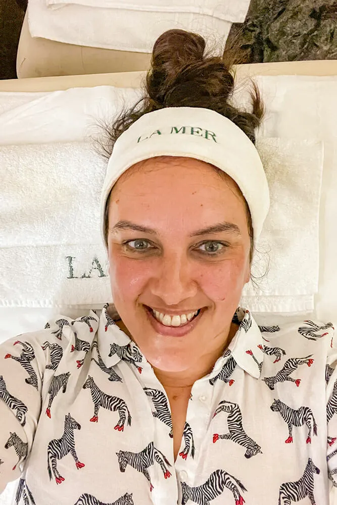 Selfie of me lying on a treatment bed wearing a white shirt with zebras and a La Mer head band ready for my facial