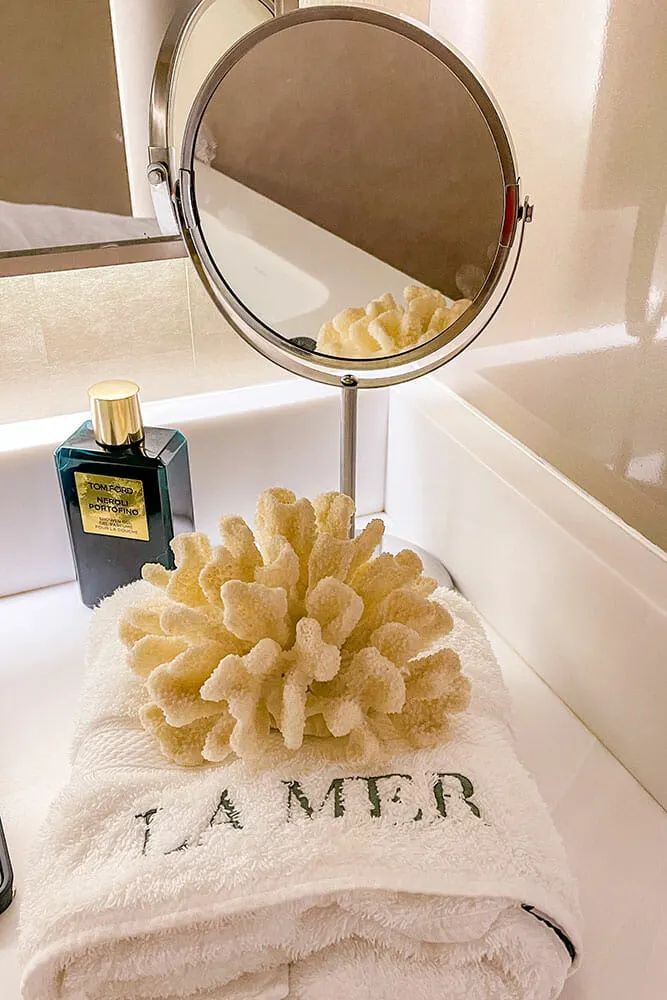 Towel with La Mer embroidery, a piece of coral and a small mirror on a counter
