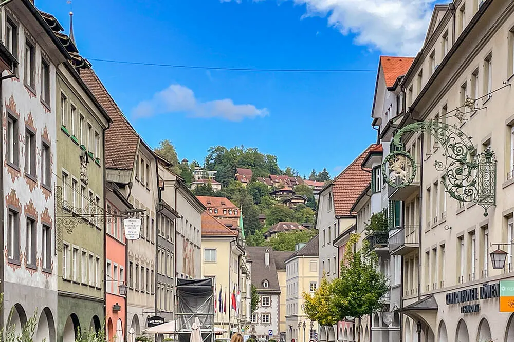 Street linked up with three-storey medieval houses and a green hill in the distance