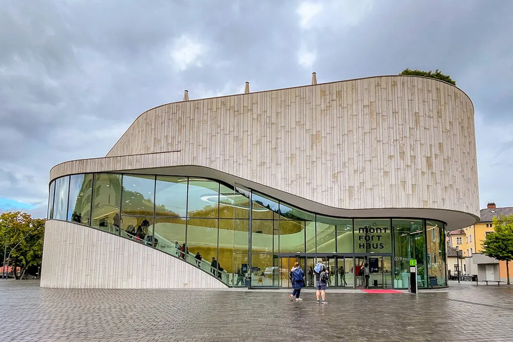 Modern building with a curving glass and wood fa&ccedil;ade in the middle of a cobblestoned square