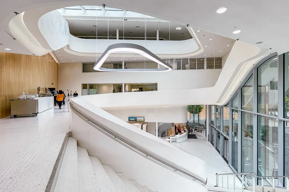 Interior of the lobby of a modern building. Everything is painted white and there are very clean wrap around lines