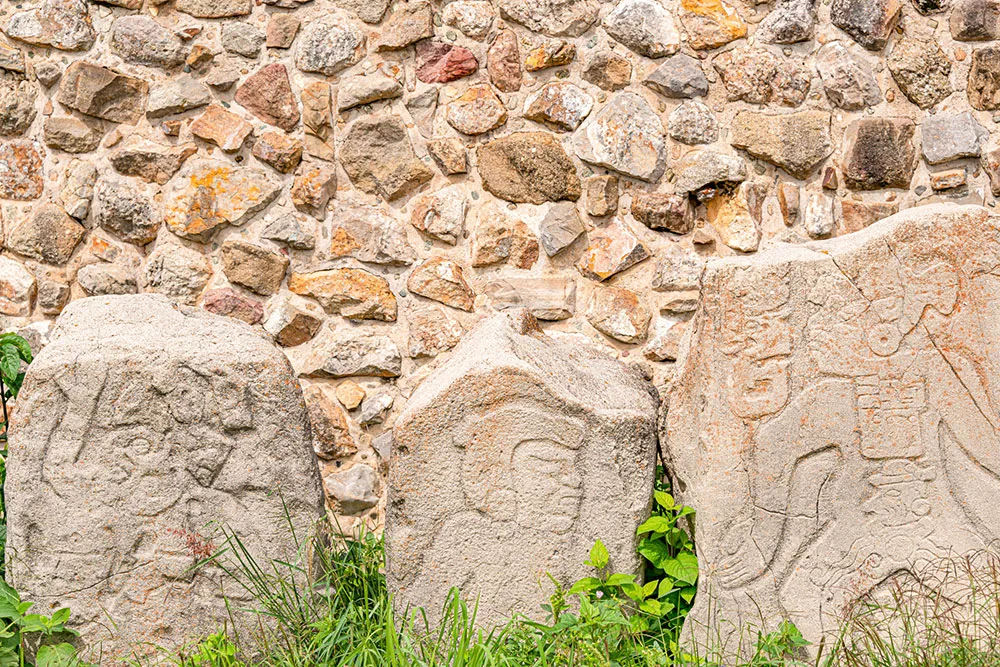 stone carvings showing the Zapotec civilization in the foreground with stone walls at the back