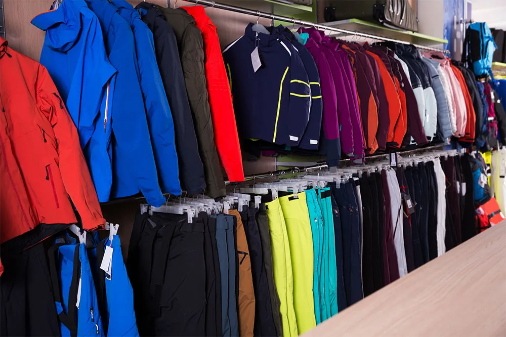 Store racks filled with snow hiking gears of based layer clothing and padded long sleeve jacket and hiking pants in store.