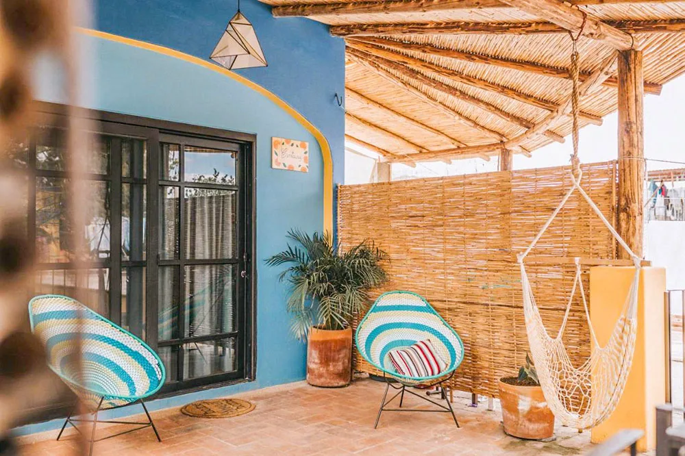 An outdoor space with blue wicker chairs with wooden walls and roof of a blue buildings