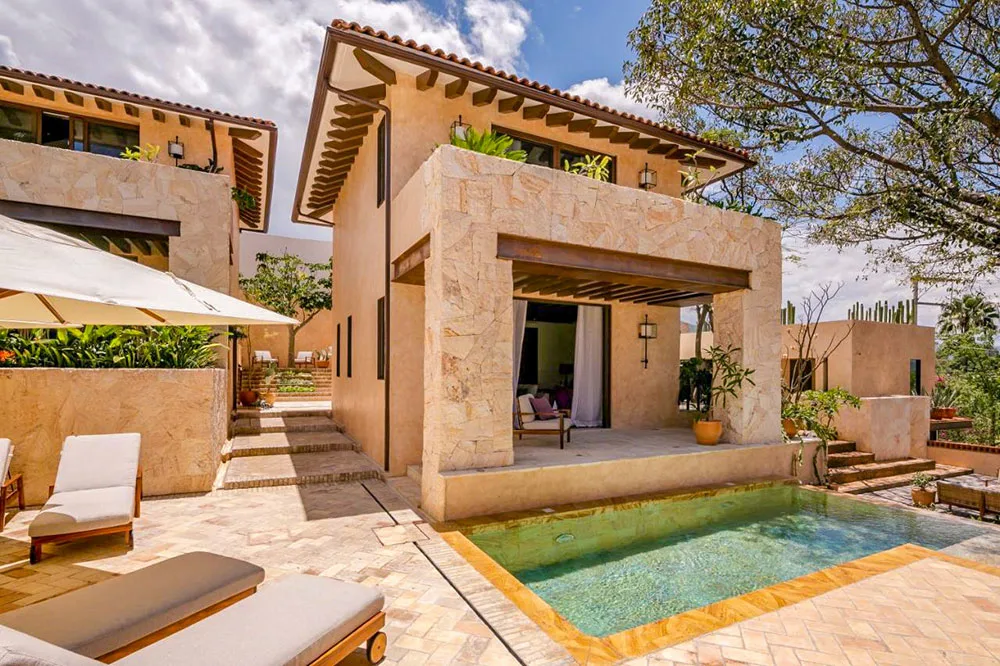 An outdoor view of the building painted in warm colors and brown tiles from the pool side with clear pool