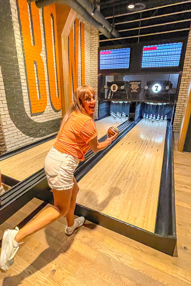 Me throwing a small bowling ball in a bowling alley with another one at the side with the score screen on top of them while surrounded by colorful bricked walls of the Shorty’s Pins x Pints in Pittsburg.
