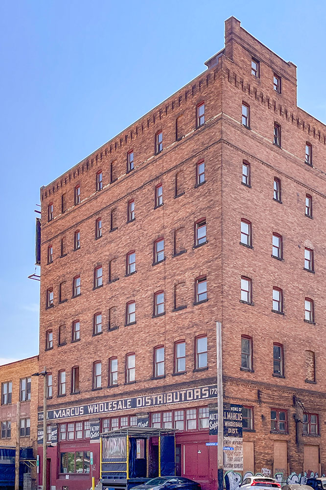 A corner view of a high rise bricked wall with several glass push up windows of a wholesale business under clear blue skies in weekend in Pittsburgh.