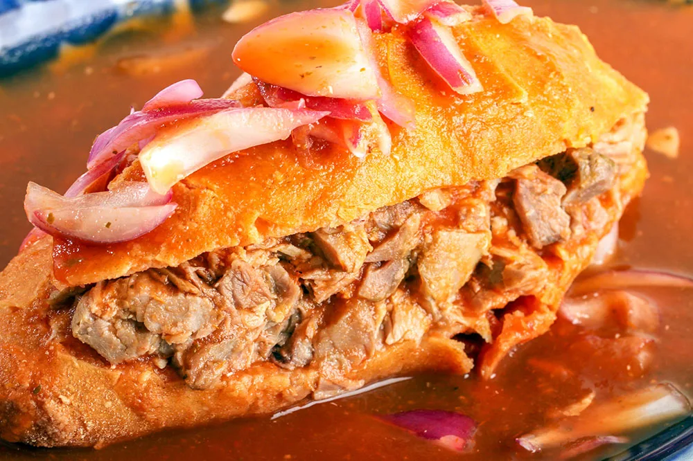 Torta filled with meat slices, drowned in sauces and topped with onion slices