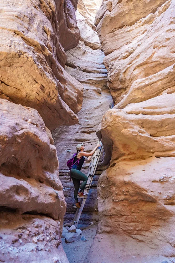 A hiker climbing up to the tall walls of a canyon. The Ladder Canyon Trails is one of the best hidden gems in Southern California.
