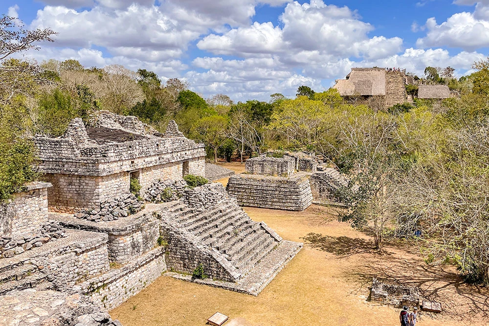 The ruins of the Zona Arqueol&oacute;gica de Ek Balam covered by trees under bright cloudy skies making it the top places to visit in Yucatan Mexico