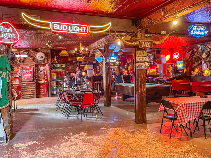 Inside a restaurant with people dining, a pool table, and decorated in neon lights