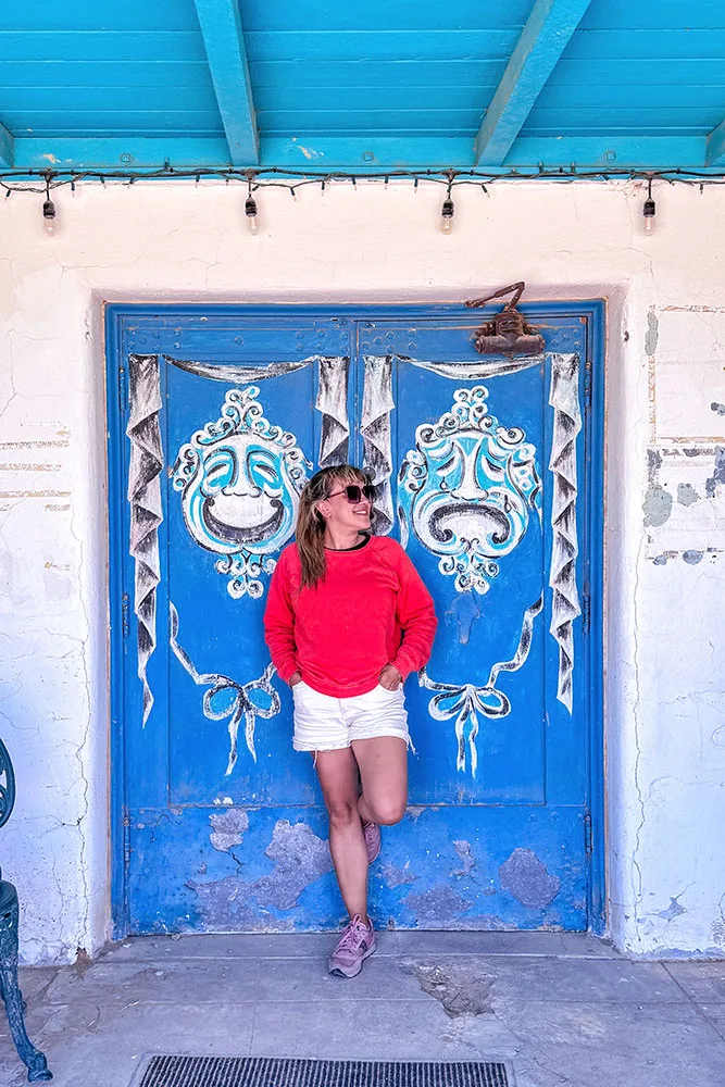 me in read blouse and white shorts leading to a wall with blue painted double doors, a stopover during road trips in nevada
