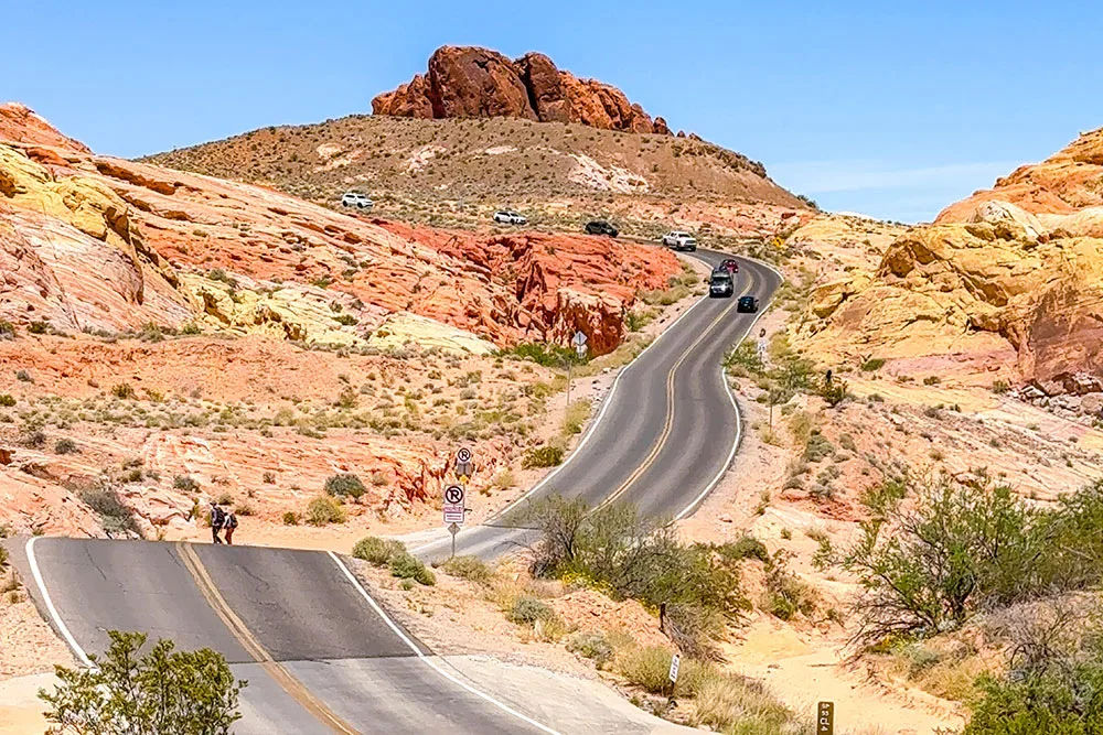 cars going down hill on the road in between an open desert for road trips in nevada