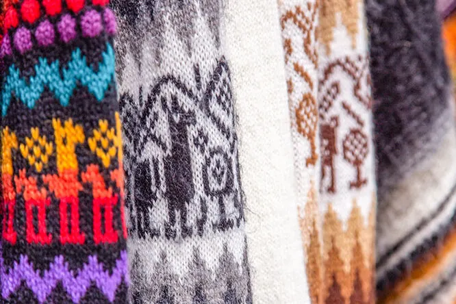 Knitted scarves with a variety of patterns in bright colors and dark colors of brown, black, and gray. These are some of the best souvenirs from Peru.